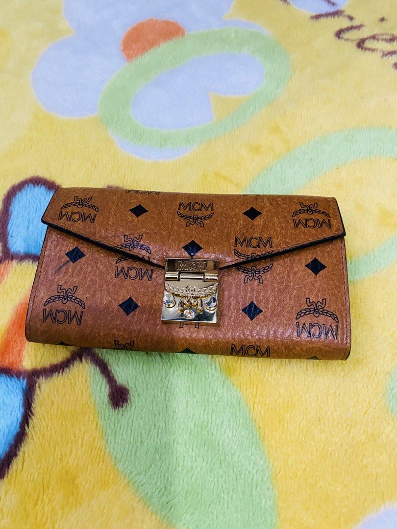 MCM Visetos Trifold Wallet Cognac (Category: Luxury Bags & Wallets) located in San Jose del Monte. Submitted by cityhanter007 (Listing ID 1457264852, Image 1). Description: - Authentic MCM wallet - Signature Visetos print - Gold-tone lock closure - Multiple card slots - Genuine leather interior - flaws: minimal fadings on hardware and may konting bakbak sa loob ng bag.