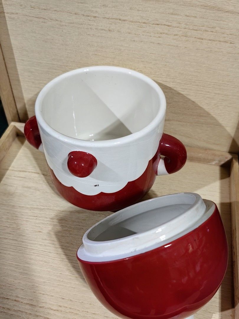 Santa ceramic jar with lid (Category: Other Kitchenware & Tableware) located in Calamba. Submitted by princesspauliney. (Listing ID 1457267367, Image 2). Description: whimsical ceramic canister is shaped like a round Santa Claus on skis. It features a glossy red glazed body and cap, accented with a large red nose and a wavy white beard. It serves as a holiday treat or cookie canister that pulls apart at the middle to reveal a food-safe storage co