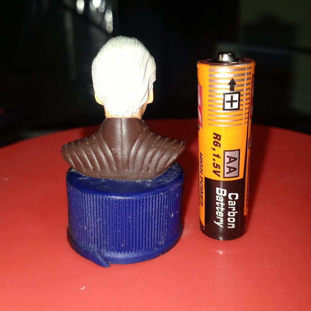 Star Wars Count Dooku Bust Figure (Category: Figurines & Statues) located in Binan City. Submitted by kariray_shop (Listing ID 1457322182, Image 2). Description: - Miniature bust of Count Dooku from Star Wars. - Mounted on a blue bottle cap. - Stands next to an AA battery for size reference. - Ideal for collectors and Star Wars fans. - Unique desk decoration..