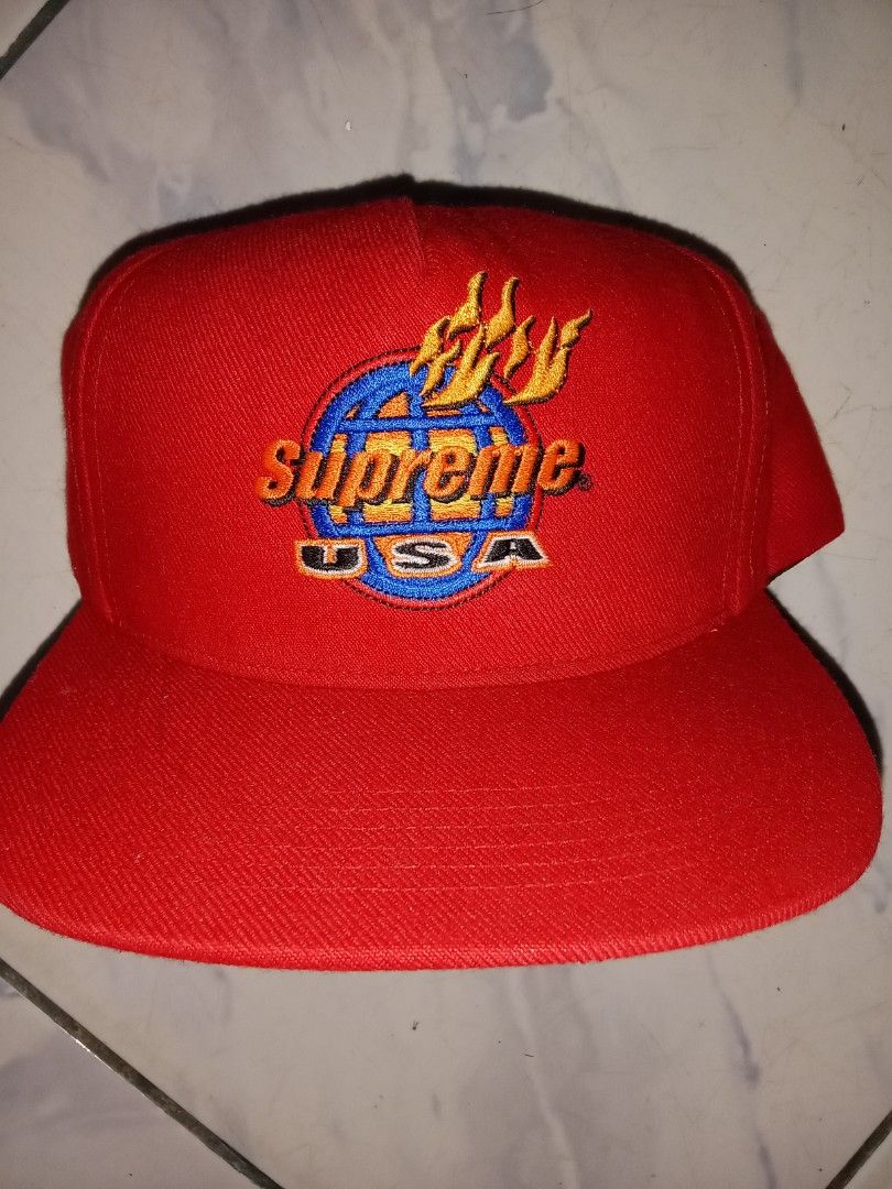 Supreme USA Globe Flames Red Snapback Hat (Category: Caps & Hats) located in Iloilo. Submitted by bakerzero8 (Listing ID 1457316391, Image 1). Description: - Authentic Red Supreme Snapback Cap - Iconic globe with flames logo on the front - 'Supreme' text embroidered on the back - 'Made in USA' tag visible - Adjustable snap closure for a custom fit.