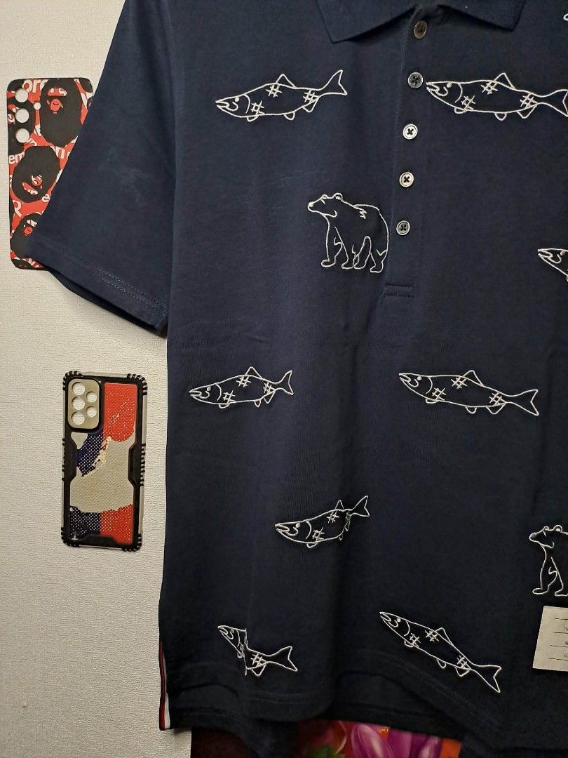 Thom Browne Bear and Salmon (Category: Luxury Apparel) located in Manila. Submitted by yaseen_73 (Listing ID 1457143117, Image 3). Description: Authentic Thom Browne Bear and Salmon Embroidered Polo Shirt, specifically featuring an all-over cartoon-style line embroidery of grizzly bears and stitched salmon Made in Japan Wearing Size : No. 2 Dimensions : W20 L26'27 Color Rate : 9.9/10 With Stain Issue Needs Proper Hand Wash (See Last Photo) No Lin