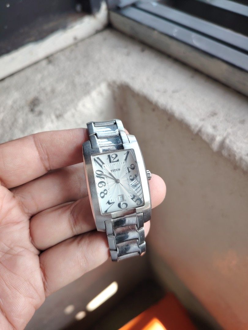Titus Rectangular Watch (Category: Watches) located in Cheras. Submitted by onemuhaimin (Listing ID 1457157633, Image 2). Description: - Titus watch - Silver-tone metal strap - Rectangular face with silver dial - Arabic numerals at 12, 3, 6, 9 - Date window at 3 o'clock - Minor scratches on casing and strap - Overall, a nice piece.