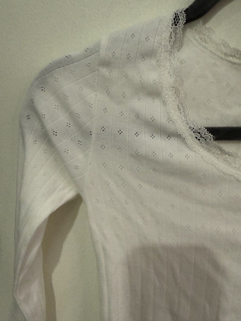 White Pointelle Knit Long Sleeve Top (Category: Longsleeves) located in Muntinlupa City. Submitted by jtarchive (Listing ID 1457256970, Image 2). Description: - Brandy Melville similar long sleeve top - Ribbed material - Delicate lace trim neckline - Small eyelet details on shoulders and sleeves - Cute and dainty design - Ideal for layering or wearing solo.