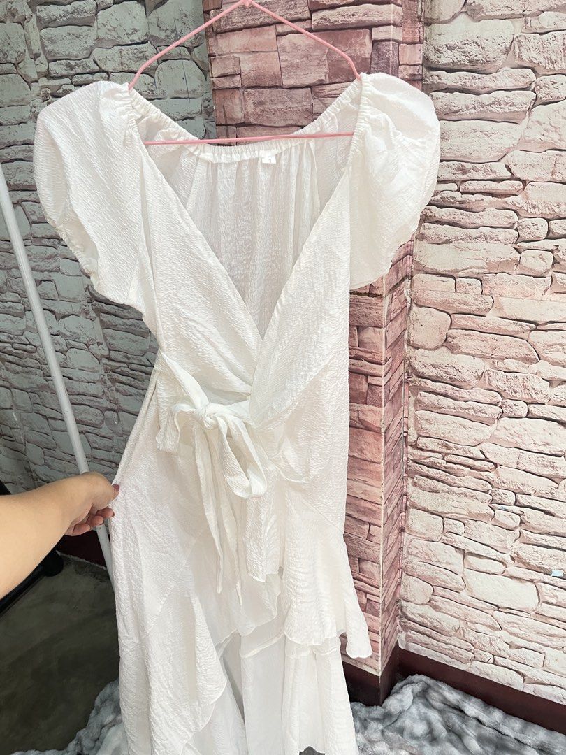 White Puff Sleeve Wrap Dress with Ruffle Hem (Category: Dresses) located in Quezon City. Submitted by queenthingss (Listing ID 1457296476, Image 3). Description: - Flowy white wrap dress - Short puff sleeves - Tie waist for adjustable fit - Ruffled high-low hem - Textured crinkle fabric effect - Versatile for casual outings or beach vacations - Easy to dress up or down XS-Small frame.