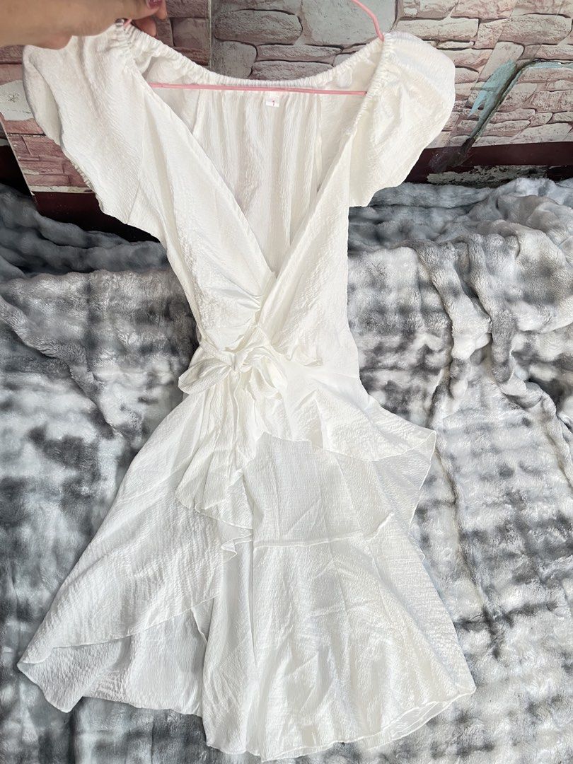 White Puff Sleeve Wrap Dress with Ruffle Hem (Category: Dresses) located in Quezon City. Submitted by queenthingss (Listing ID 1457296476, Image 2). Description: - Flowy white wrap dress - Short puff sleeves - Tie waist for adjustable fit - Ruffled high-low hem - Textured crinkle fabric effect - Versatile for casual outings or beach vacations - Easy to dress up or down XS-Small frame.