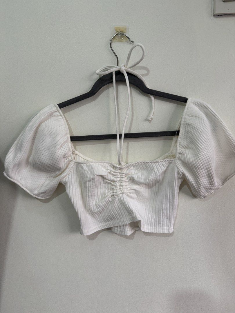 ZARA White Puff Sleeve Ruched Crop Top (Category: Blouses) located in Muntinlupa City. Submitted by jtarchive (Listing ID 1457255133, Image 1). Description: - White ribbed crop top from ZARA - Size: Medium (M) - Trendy puff sleeves - Flattering ruched front detail - Chic square neckline with tie-up halter neck - Versatile: pairs perfectly with jeans or skirts.