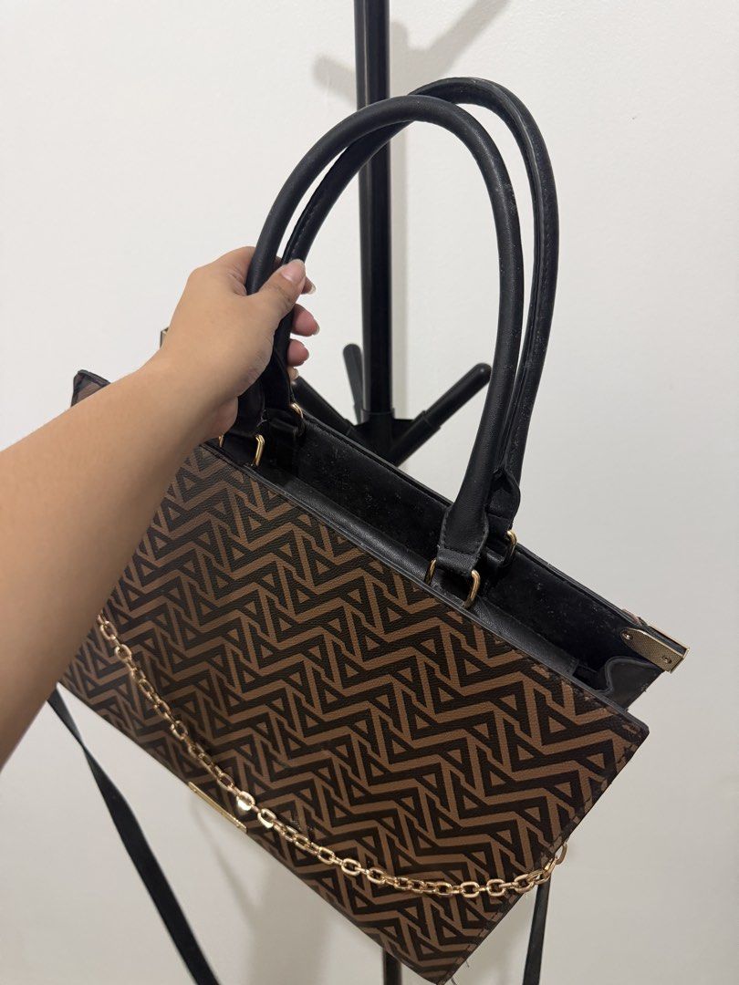 ALDO Monogram Tote Bag with Chain Detail (Category: Luxury Bags & Wallets) located in Manila. Submitted by dnnmrl (Listing ID 1457473879, Image 3). Description: - Stylish ALDO tote bag in brown and black. - Features the signature ALDO monogram print. - Elegant gold chain detail across the front. - Includes comfortable top handles. - Comes with a detachable shoulder strap for versatility. - Shows some signs of wear on handles and strap, adding cha