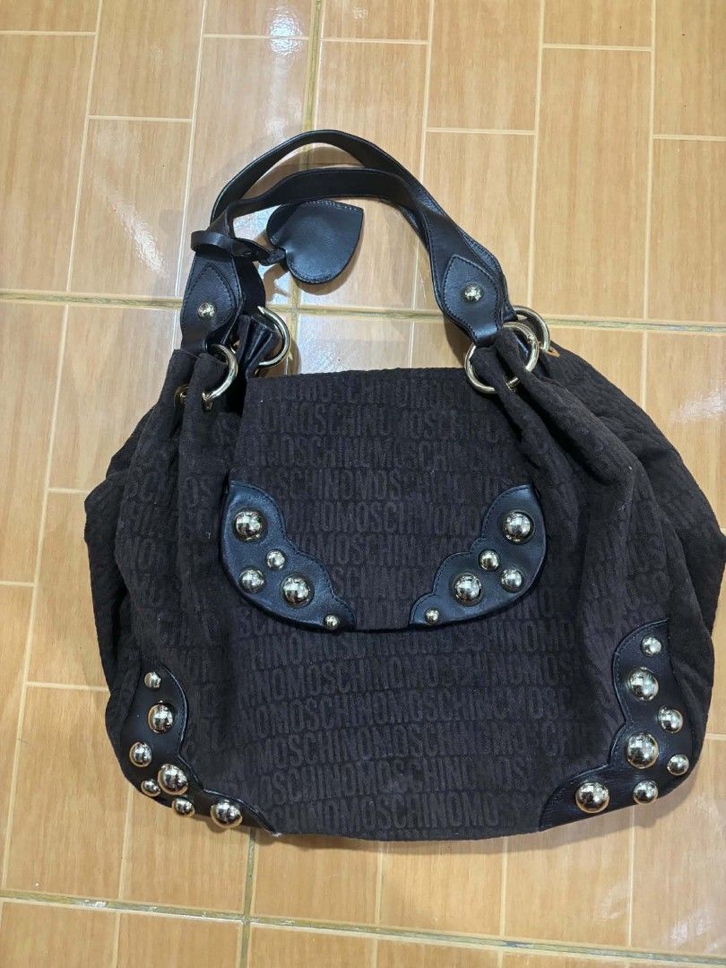 Brown Moschino Monogram Shoulder Bag with Studs (Category: Luxury Bags & Wallets) located in Paranaque City. Submitted by poego (Listing ID 1457449026, Image 1). Description: - Authentic Moschino shoulder bag in classic brown. - Features the signature all-over monogram pattern. - Accented with stylish black leather trim and elegant gold-tone studs. - Offers a spacious interior with a convenient zippered pocket for essentials. - Equipped with doub