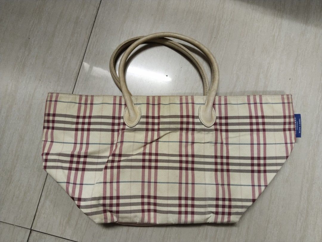 Burberry Blue Label Plaid Tote Bag (Category: Luxury Bags & Wallets) located in Pasay City. Submitted by emelsthrift1997 (Listing ID 1457420843, Image 2). Description: - Authentic Burberry Blue Label tote bag - Iconic Burberry plaid pattern (beige base with maroon and blue lines) - Durable leather handles - Luxurious pink satin interior lining - Shows some signs of wear on handles and exterior fabric - Perfect for stylish everyday use issue: sign