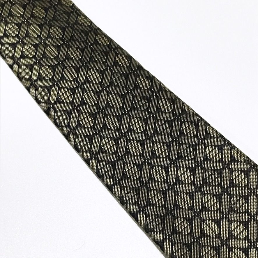 D'URBAN Black Repeating Geometric Textured Neck Tie (Category: Ties) located in Taguig. Submitted by retrogaze (Listing ID 1457368695, Image 3). Description: This 100% polyester necktie by D'URBAN features a deep black base woven with a crisp, structured stiffness. The body displays a dense, repeating geometric lattice pattern of interlocking circular and oval links highlighted in metallic champagne-gold thread against the dark ground. Recommende