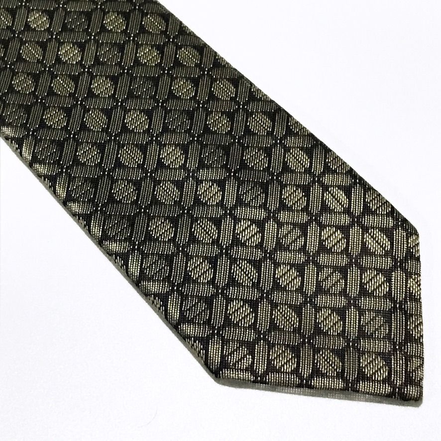 D'URBAN Black Repeating Geometric Textured Neck Tie (Category: Ties) located in Taguig. Submitted by retrogaze (Listing ID 1457368695, Image 2). Description: This 100% polyester necktie by D'URBAN features a deep black base woven with a crisp, structured stiffness. The body displays a dense, repeating geometric lattice pattern of interlocking circular and oval links highlighted in metallic champagne-gold thread against the dark ground. Recommende