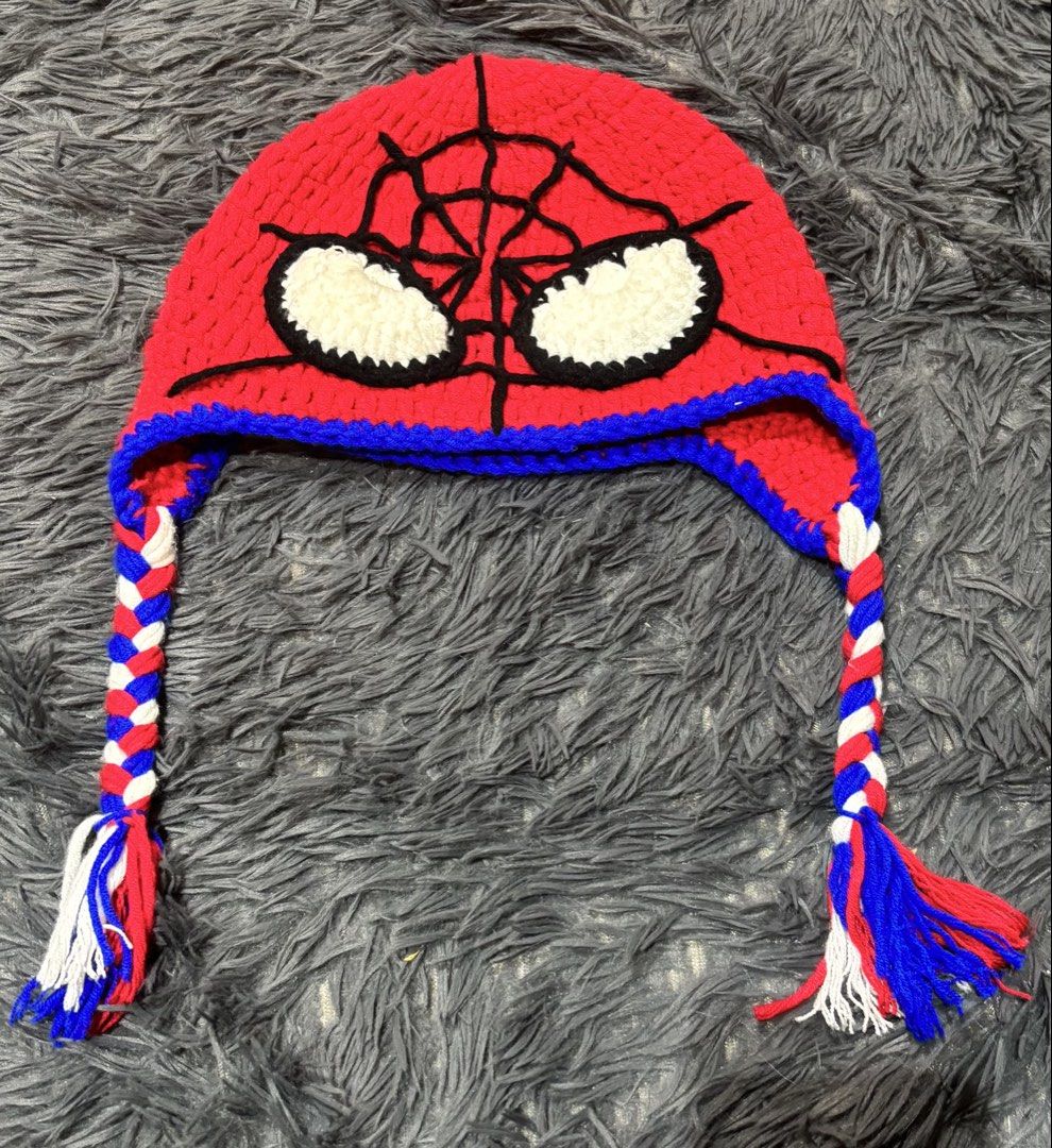 Handmade Spiderman Crochet Beanie Hat with Braids (Category: Hats & Beanies) located in Naga. Submitted by fibonacci7 (Listing ID 1457378969, Image 1). Description: - Red crochet beanie with Spiderman face design - Features white eyes with black outline and red webbing - Blue trim around the face - Two braided tassels with red, white, and blue yarn - Ideal for Spiderman fans and keeping warm.