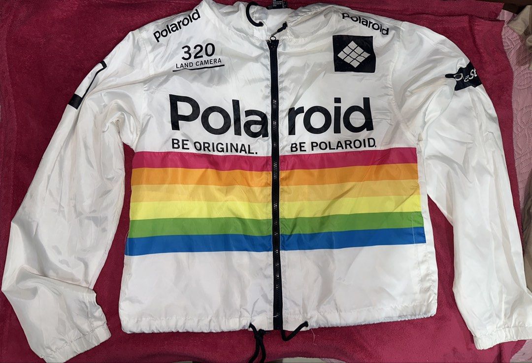 Polaroid White Windbreaker Jacket Rainbow Stripe (Category: Coats, Jackets and Outerwear) located in Manila. Submitted by klmesco (Listing ID 1457477219, Image 2). Description: White Polaroid windbreaker jacket with Hoodie - bought in Forever 21 - Features classic rainbow stripe across the chest - '320 LAND CAMERA' and Polaroid logos - Drawstring hem for adjustable fit - Minor stains (shown in pics) RFS: Decluttering and need funds! 🥹.
