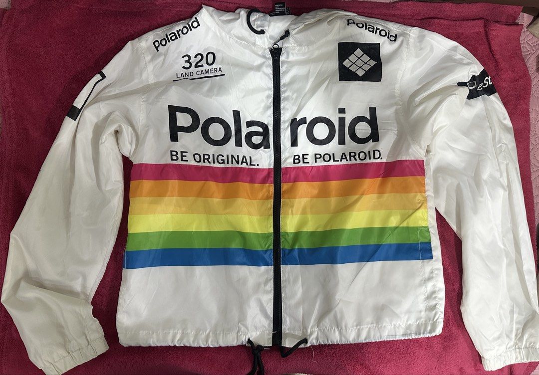 Polaroid White Windbreaker Jacket Rainbow Stripe (Category: Coats, Jackets and Outerwear) located in Manila. Submitted by klmesco (Listing ID 1457477219, Image 1). Description: White Polaroid windbreaker jacket with Hoodie - bought in Forever 21 - Features classic rainbow stripe across the chest - '320 LAND CAMERA' and Polaroid logos - Drawstring hem for adjustable fit - Minor stains (shown in pics) RFS: Decluttering and need funds! 🥹.