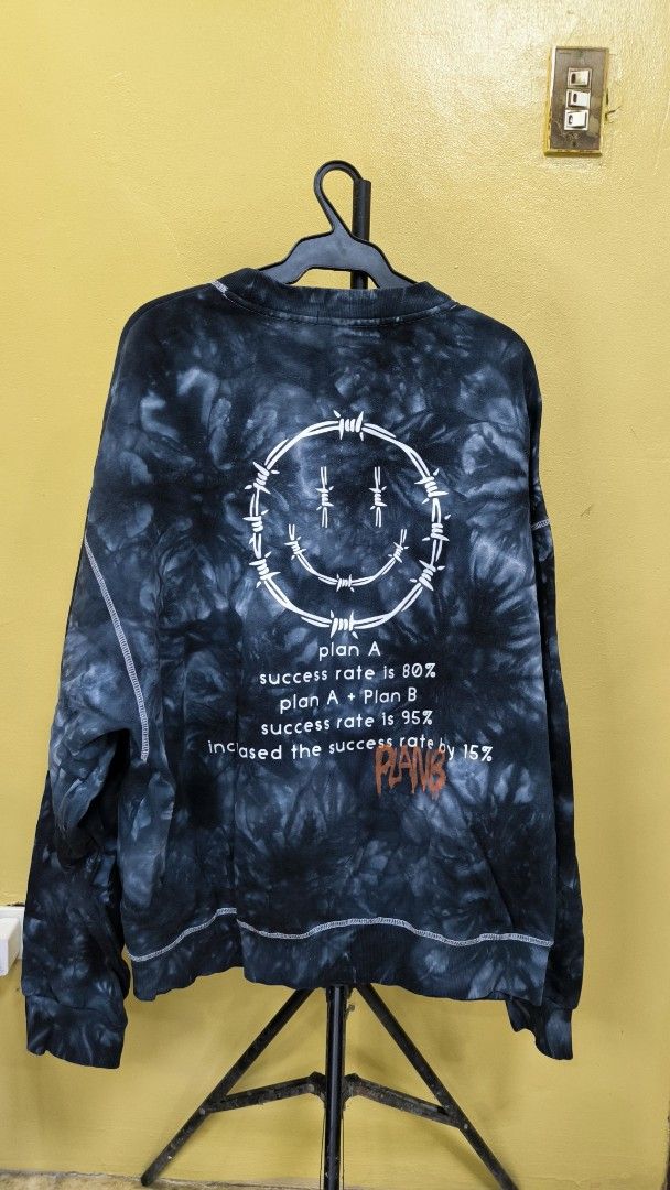 Tie-dye Smiley Face Barbed Wire Graphic Sweatshirt (Category: Longsleeves) located in Antipolo. Submitted by thrift.trippin (Listing ID 1457418532, Image 2). Description: - Black and grey tie-dye sweatshirt - Graphic on back with smiley face and text - White contrast stitching throughout - Crew neck, long sleeves - Estimated size Medium/Large (please check measurements) - Ideal for casual wear.