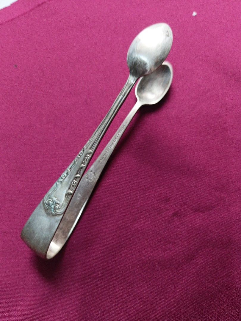 Vintage Silver Sugar Tongs with Spoon Ends (Category: Dinnerware & Cutlery) located in Batangas. Submitted by lavu4555 (Listing ID 1457373593, Image 3). Description: - Antique silver color sugar tongs - Features two small spoon ends for serving - Ornate detailing on the handles - Ideal for sugar cubes or small appetizers - Adds vintage charm to kitchen or tea set.
