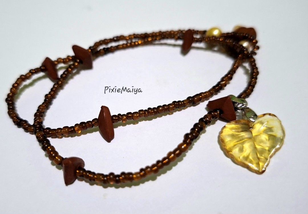 Beaded Necklace with Leaf Pendant (Category: Necklaces) located in Valenzuela. Submitted by pixieworks64309 (Listing ID 1457709235, Image 1). Description: - Unique handmade brown beaded necklace - Features wooden accents - Translucent yellow leaf pendant - Includes small cream-colored beads - Adorned with a flower-shaped bead - Adds a natural touch to any outfit.
