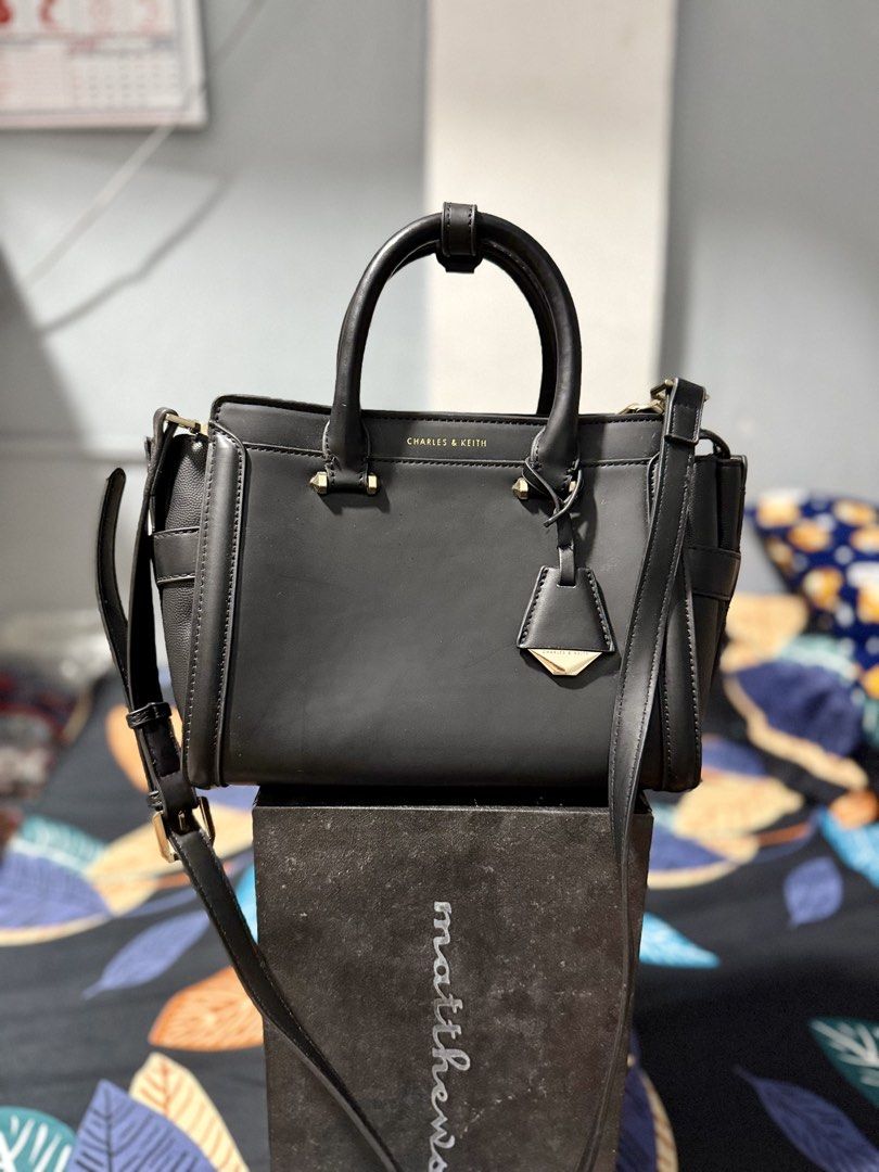 Charles & Keith Black Top Handle Bag (Category: Luxury Bags & Wallets) located in Manila. Submitted by bags.shopp (Listing ID 1457658162, Image 1). Description: - Mall pullout Charles & Keith handbag in black. - Versatile with top handles and a detachable shoulder strap. - Elegant gold hardware details. - Spacious interior with zippered pockets and compartments. - Clean and well-maintained inside. - Ideal for everyday use..