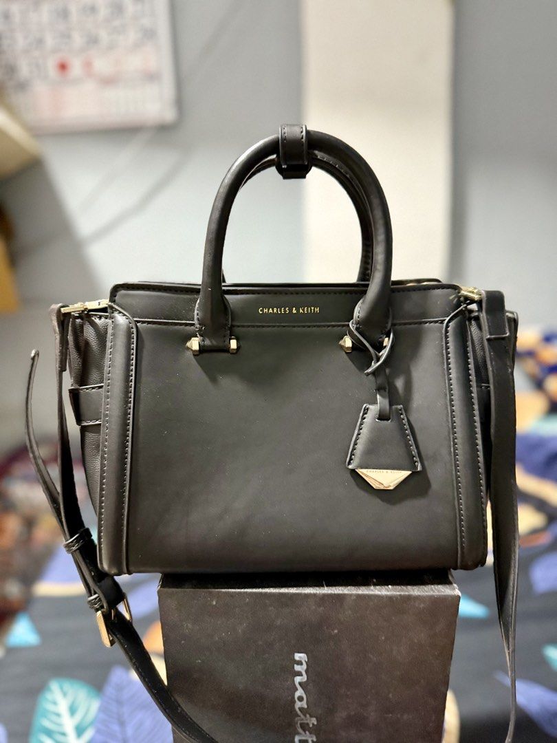 Charles & Keith Black Top Handle Bag (Category: Luxury Bags & Wallets) located in Manila. Submitted by bags.shopp (Listing ID 1457658162, Image 3). Description: - Mall pullout Charles & Keith handbag in black. - Versatile with top handles and a detachable shoulder strap. - Elegant gold hardware details. - Spacious interior with zippered pockets and compartments. - Clean and well-maintained inside. - Ideal for everyday use..