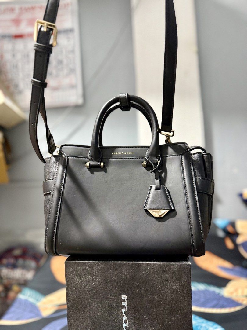 Charles & Keith Black Top Handle Bag (Category: Luxury Bags & Wallets) located in Manila. Submitted by bags.shopp (Listing ID 1457658162, Image 2). Description: - Mall pullout Charles & Keith handbag in black. - Versatile with top handles and a detachable shoulder strap. - Elegant gold hardware details. - Spacious interior with zippered pockets and compartments. - Clean and well-maintained inside. - Ideal for everyday use..