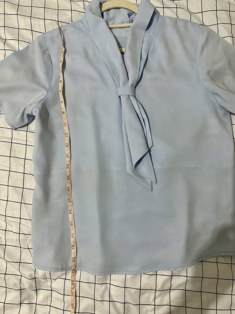 Light Blue Short Sleeve Blouse with Tie Neck (Category: Blouses) located in Manila. Submitted by salmongirl88 (Listing ID 1457635348, Image 2). Description: - Light blue short-sleeved blouse - Elegant tie-neck detail - Fabric with a subtle sheen - Measurements: Approx. 23" length, 19" chest (pit to pit) - Versatile: Great for work or casual wear - Easy to style.