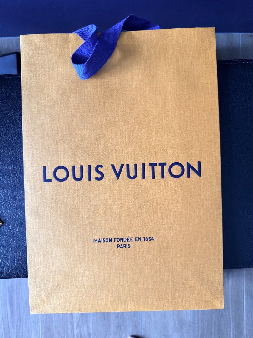 Louis Vuitton Shopping Bag (Category: Luxury Bags & Wallets) located in Marikina City. Submitted by teacher.maria (Listing ID 1457524794, Image 1). Description: - Authentic Louis Vuitton shopping bag - Color: Beige with blue ribbon handles - Features: Louis Vuitton logo and 'Maison Fondée en 1854 Paris' text - Condition: Good - Ideal for: Gifting or storing small items.