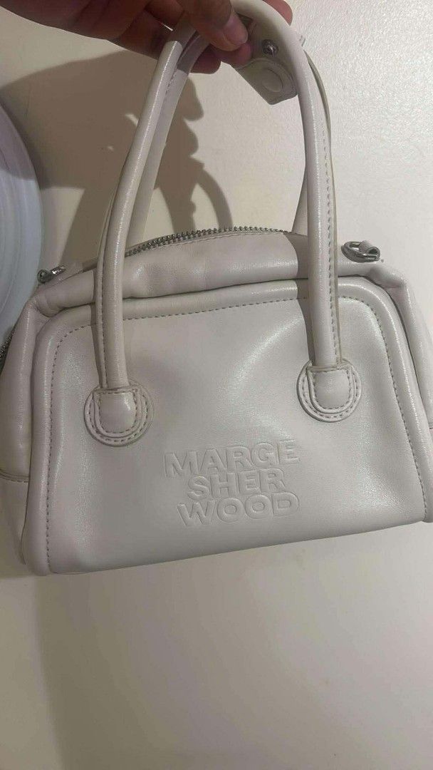 MARGE SHERWOOD White Leather Top Handle Bag (Category: Luxury Bags & Wallets) located in Bay. Submitted by silverhorse-59c851 (Listing ID 1457528231, Image 1). Description: - Brand: MARGE SHERWOOD - Color: White - Material: Leather - Origin: Made in Korea - Closure: Top zip - Handles: Two top handles - Condition: Some signs of wear on handle edges, as pictured - Interior: Branded tag - Style: Classic, suitable for everyday use.