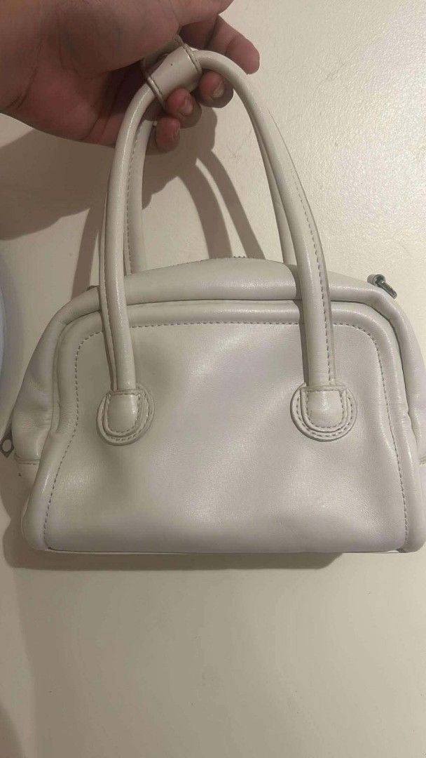 MARGE SHERWOOD White Leather Top Handle Bag (Category: Luxury Bags & Wallets) located in Bay. Submitted by silverhorse-59c851 (Listing ID 1457528231, Image 2). Description: - Brand: MARGE SHERWOOD - Color: White - Material: Leather - Origin: Made in Korea - Closure: Top zip - Handles: Two top handles - Condition: Some signs of wear on handle edges, as pictured - Interior: Branded tag - Style: Classic, suitable for everyday use.