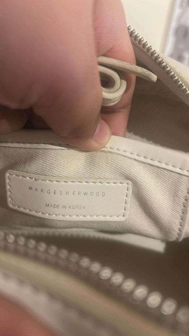 MARGE SHERWOOD White Leather Top Handle Bag (Category: Luxury Bags & Wallets) located in Bay. Submitted by silverhorse-59c851 (Listing ID 1457528231, Image 3). Description: - Brand: MARGE SHERWOOD - Color: White - Material: Leather - Origin: Made in Korea - Closure: Top zip - Handles: Two top handles - Condition: Some signs of wear on handle edges, as pictured - Interior: Branded tag - Style: Classic, suitable for everyday use.