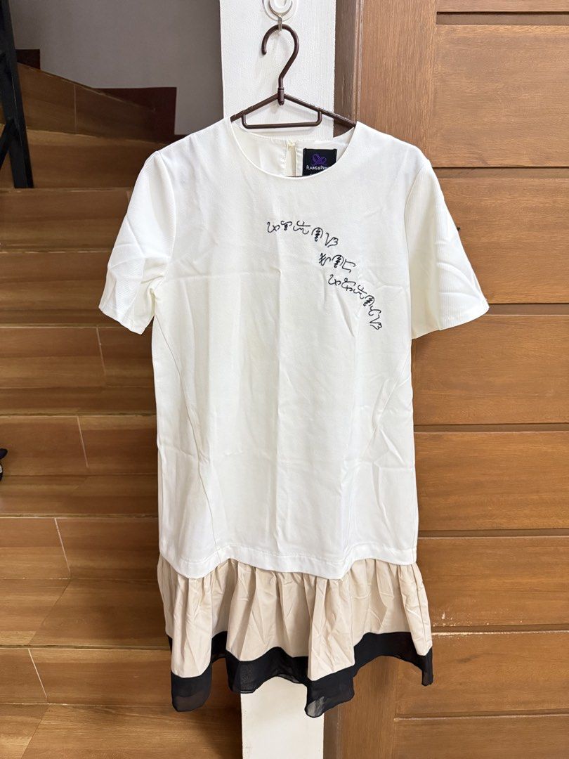 Plains & Prints White Dress with Ruffle Hem (Category: Dresses) located in Cavite. Submitted by katsibulo (Listing ID 1457646104, Image 1). Description: - Brand: Plains & Prints - Color: White - Size: Approximately size 4 - Design: Unique graphic print on chest - Hem: Layered ruffle detail in beige and black - Sleeves: Short sleeves.