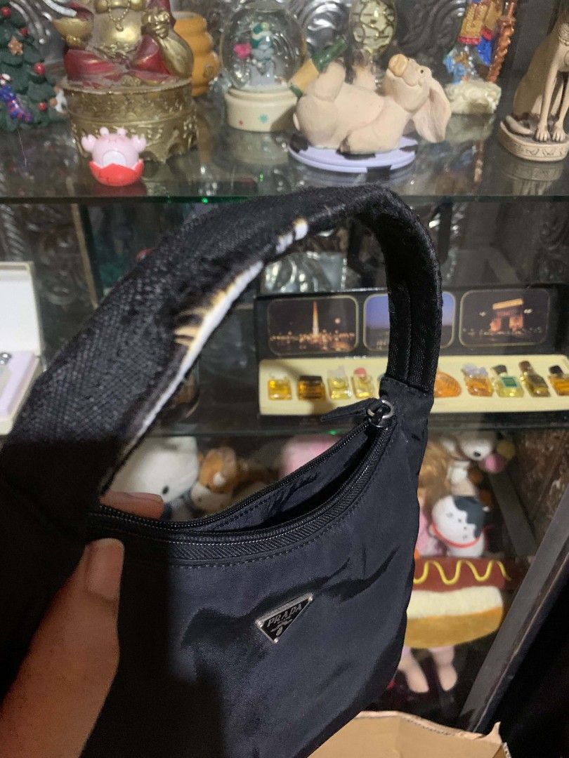 Prada Nylon Mini Bag Black (Category: Luxury Bags & Wallets) located in Gapan. Submitted by cleverstar.36492b (Listing ID 1457594336, Image 3). Description: Authentic Prada mini bag. Black nylon material. Classic triangle logo on the front. Zipper closure. Handle shows some signs of wear. Interior is clean. Made in Italy. Great for essentials..