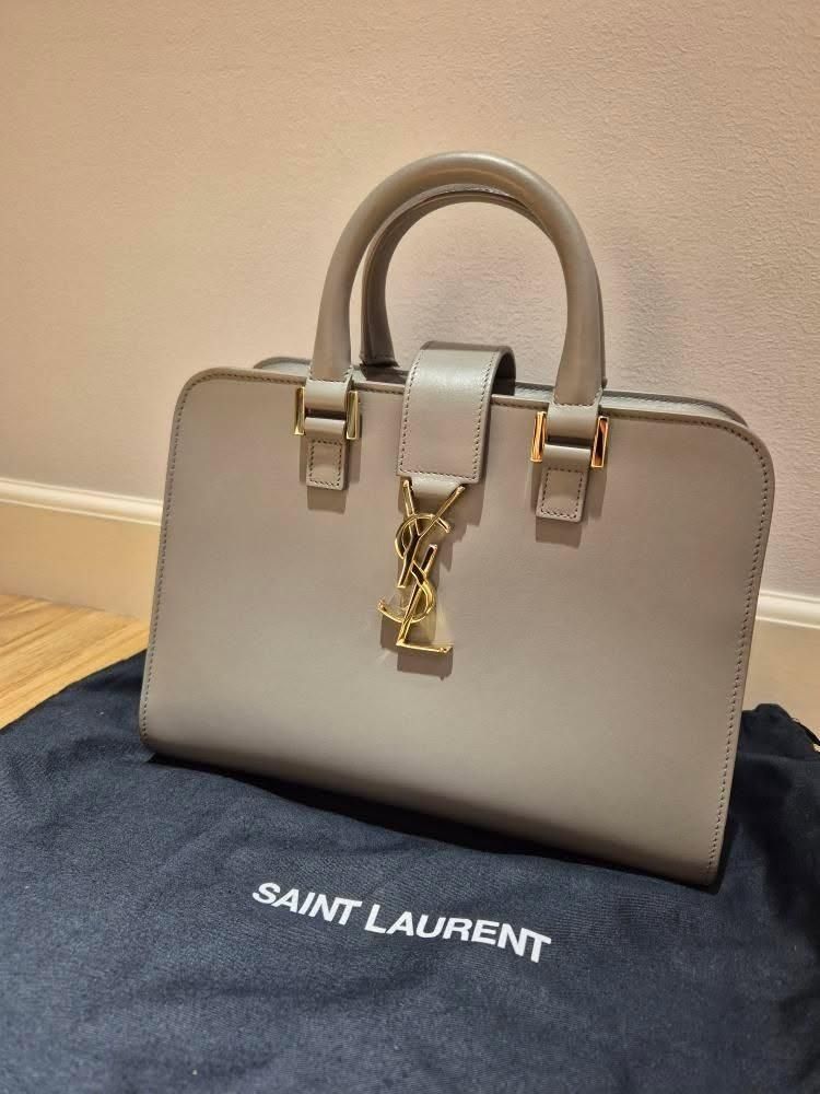Saint Laurent Baby Cabas Bag (Category: Luxury Bags & Wallets) located in Paranaque City. Submitted by happyfindsbyc (Listing ID 1457610094, Image 1). Description: - Authentic Saint Laurent grey leather top handle bag - Features iconic gold YSL logo hardware - Comes with original dust bag - A classic and timeless piece *Bought in London *Condition: 10/10 *RFS: Decluttering.