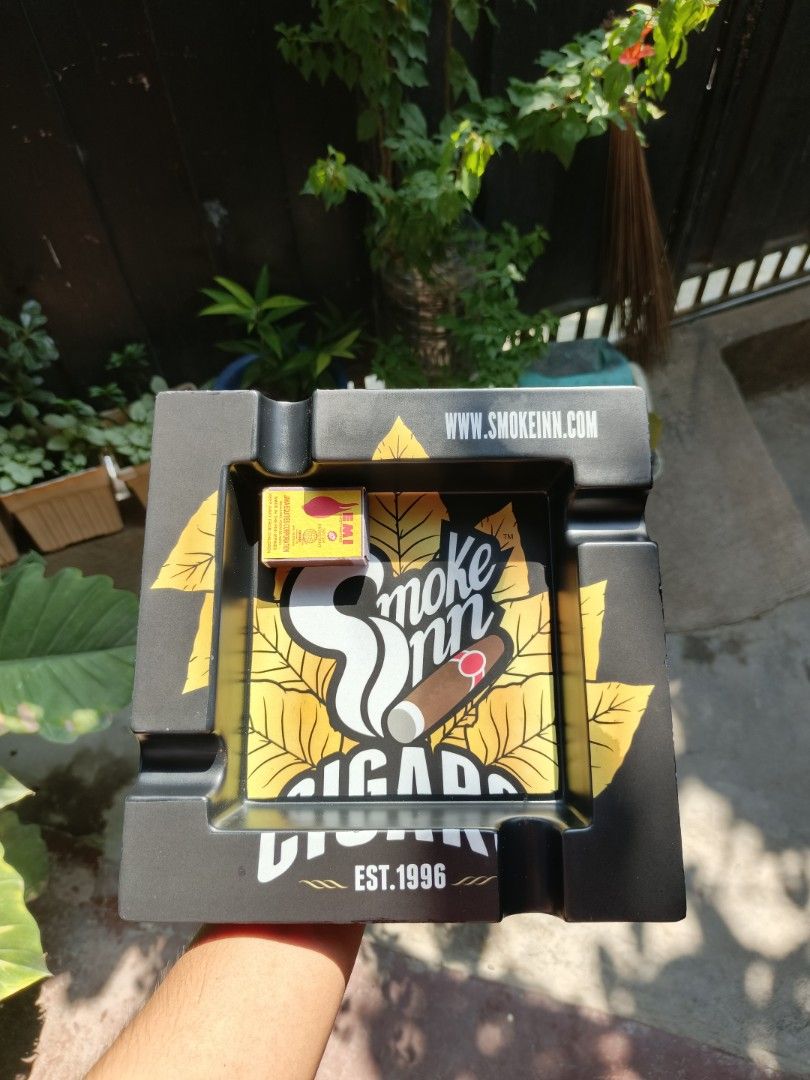 Smoke Inn Ashtray Cigar Est. 1996 (Category: Other Home Decor) located in General Santos City (Dadiangas). Submitted by goodiegoodythrift (Listing ID 1457658753, Image 1). Description: - Black ashtray with a stylish yellow leaf design. - Features the "Smoke Inn Cigar" logo and a cigar graphic. - "EST. 1996" and "WWW.SMOKEINN.COM" printed on the side. - An ideal gift for any cigar enthusiast..