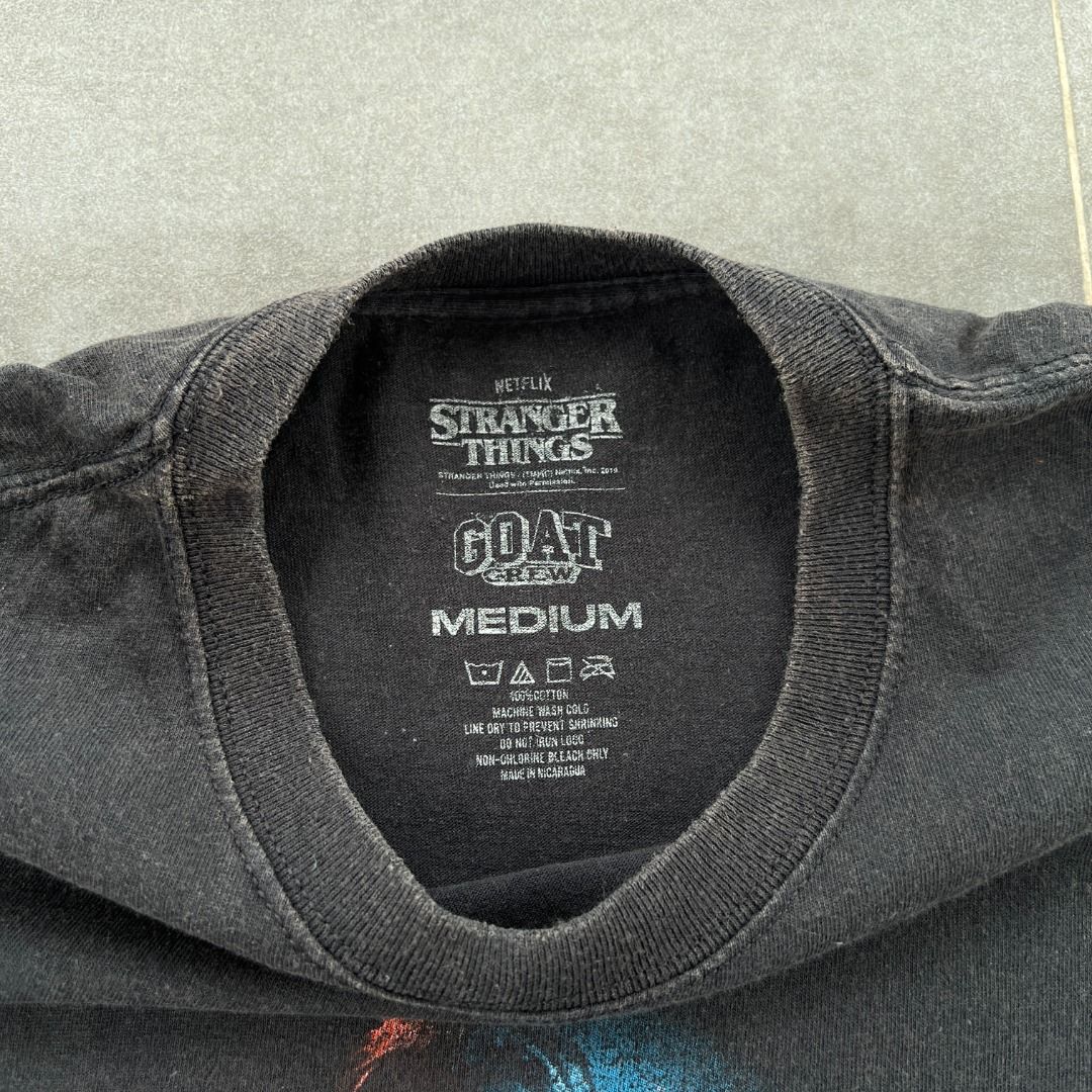 Stranger Things Character GOAT Graphic Tee Mens Medium (Category: Tshirts & Polo Shirts ) located in Talisay. Submitted by sidequested.archive (Listing ID 1457648286, Image 3). Description: 🏷️ Item Code: SQ097ae 📝Details • Condition: Pre-loved; good overall condition with a naturally faded, worn-in black finish. • Color rating: 8/10 • Size: M (on tag; see measurements for accuracy) • Measurements (in inches): 21’ W × 28’ L Overall rating: 8.5/1