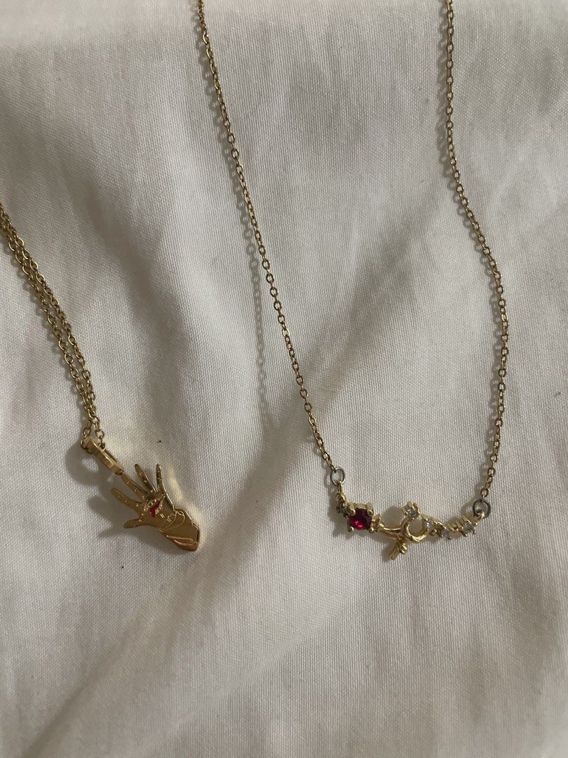 Tala by Kyla Necklaces (Category: Necklaces) located in Paranaque City. Submitted by commandercinnabutt (Listing ID 1457595173, Image 2). Description: - Set of two gold-tone necklaces - One necklace with a hand charm adorned with small red stones - Second necklace features a rose charm, a red stone, and the word 'love' - Both necklaces have delicate chains - Ideal for layering together or wearing as individual statement pieces.