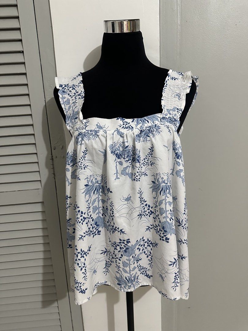 White Blue Floral Square Neck Ruffle Strap Top (Category: Blouses) located in Subic. Submitted by ruffa_assorted_item (Listing ID 1457522783, Image 1). Description: - Cute white top with a charming blue floral print. - Features a stylish square neckline and delicate ruffled straps. - Open back design with elastic at the waist for a comfortable fit. - Made from lightweight fabric, ideal for hot weather. - Versatile piece that easily pairs with sho