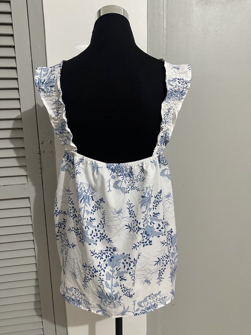 White Blue Floral Square Neck Ruffle Strap Top (Category: Blouses) located in Subic. Submitted by ruffa_assorted_item (Listing ID 1457522783, Image 2). Description: - Cute white top with a charming blue floral print. - Features a stylish square neckline and delicate ruffled straps. - Open back design with elastic at the waist for a comfortable fit. - Made from lightweight fabric, ideal for hot weather. - Versatile piece that easily pairs with sho