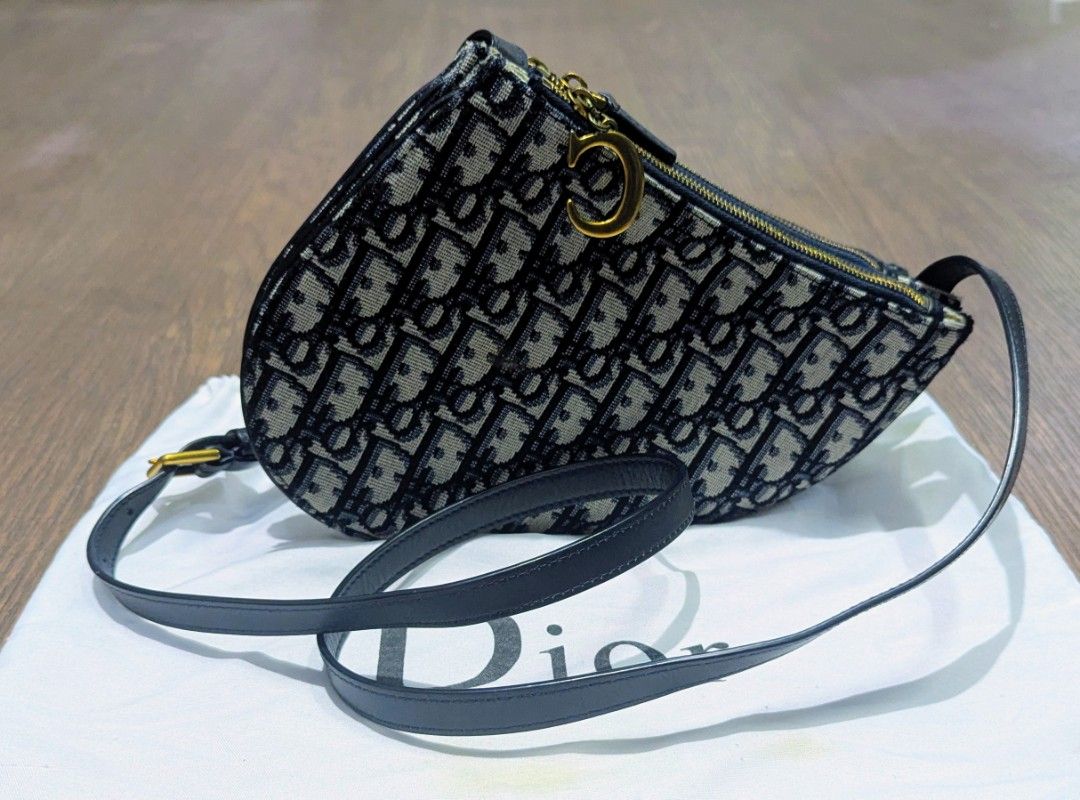 Authentic Christian Dior saddle pouch oblique (Category: Cross-body Bags) located in Baguio. Submitted by second_handchic (Listing ID 1457784320, Image 1). Description: authentic Christian Dior saddle triple zip pouch Strap in Navy Blue. This chic bag is crafted of blue and beige canvas, blue leather trim. This new classic bag features the saddlebag shape, navy leather strap with a polished gold "C" and "D" on the end of the zipper pulls. The han