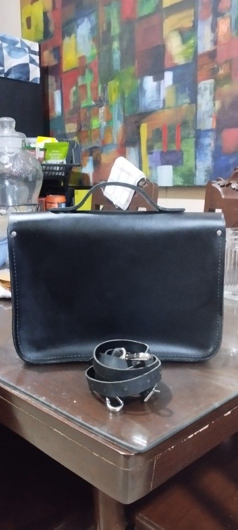 Cambridge Black Leather Satchel Bag (Category: Luxury Bags & Wallets) located in Manila. Submitted by beckster_nnline_luxuryshop (Listing ID 1457843420, Image 2). Description: - Classic black leather satchel - Red tartan fabric panel on the front 12 X 9 X 2.5 - Secure buckle closures - Comfortable top handle - Detachable shoulder strap for versatility - Roomy interior for all your essentials - Ideal for school or everyday carry SIZE: 12 X 9 X 2.5