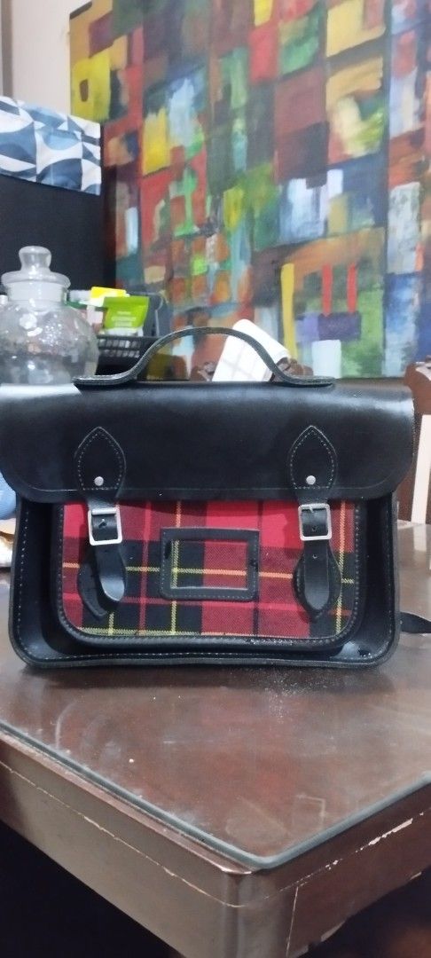 Cambridge Black Leather Satchel Bag (Category: Luxury Bags & Wallets) located in Manila. Submitted by beckster_nnline_luxuryshop (Listing ID 1457843420, Image 1). Description: - Classic black leather satchel - Red tartan fabric panel on the front 12 X 9 X 2.5 - Secure buckle closures - Comfortable top handle - Detachable shoulder strap for versatility - Roomy interior for all your essentials - Ideal for school or everyday carry SIZE: 12 X 9 X 2.5