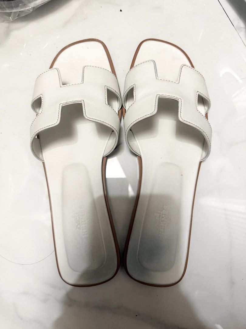 Hermes Oran Sandals White Leather (Category: Flats & Sandals) located in Manila. Submitted by karencr (Listing ID 1457754577, Image 1). Description: - Authentic Hermes Oran sandals size 39.5 - Classic white leather - Iconic 'H' design across the strap - Comfortable flat sole - Hermes Paris logo stamped on insole - Versatile for casual or dressed-up looks.