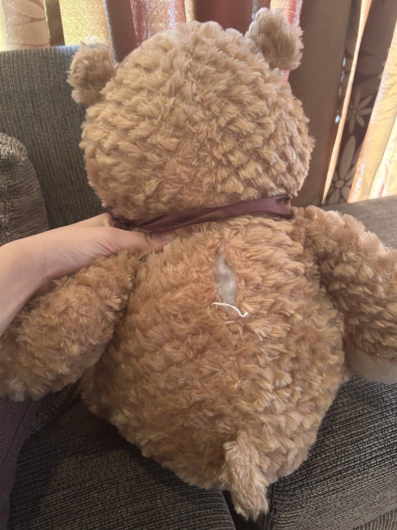 Large Brown Teddy Bear Plush Toy (Category: Plushies & Soft Toys) located in Quezon City. Submitted by bmswardrobe (Listing ID 1457761214, Image 2). Description: - Big and fluffy teddy bear - Super soft and cuddly - Features a cute ribbon around its neck - Minor tear on the back, requires a simple stitch - Ideal for hugs or as a room decoration.