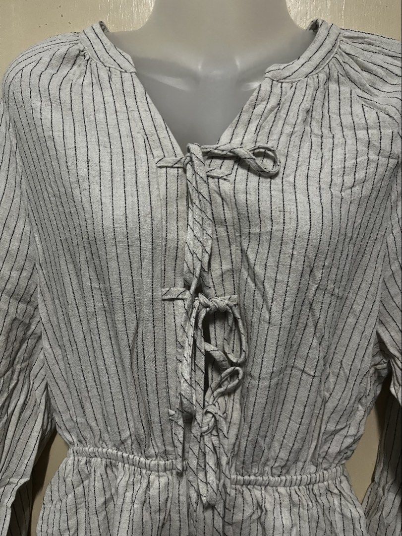Linen Striped Tie-Front Ruffle Romper (Category: Rompers) located in Tabuk. Submitted by zenwolf-1867 (Listing ID 1457859532, Image 2). Description: - Adorable grey and white striped romper - Long sleeves with a slight puff - Chic tie-front detail at the neckline - Comfortable elastic waist - Flirty ruffled hem on the shorts - Ideal for a stylish casual day out.