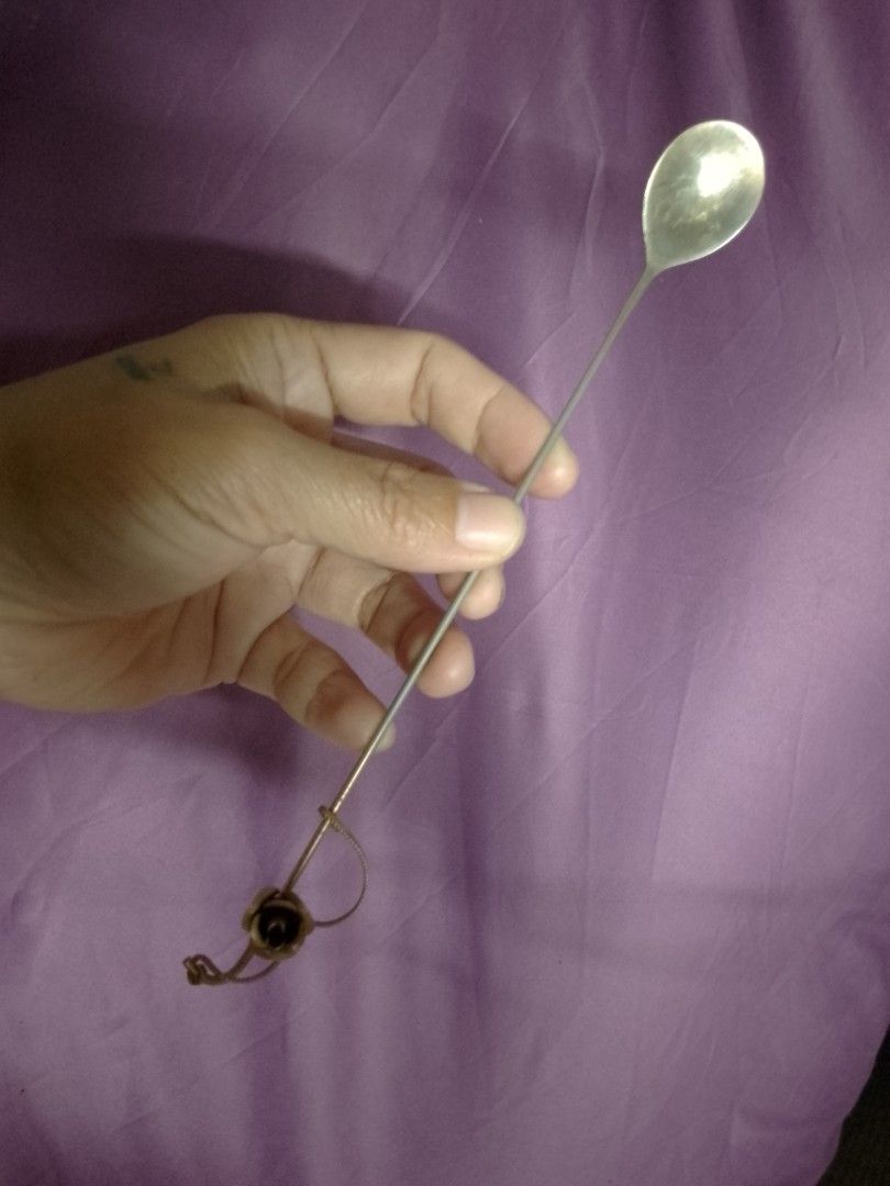Long Handle Spoon with Rose Charm (Category: Dinnerware & Cutlery) located in Cardona. Submitted by nick_and_maria (Listing ID 1457865713, Image 1). Description: - Long-handled spoon with a small spoon head. - Thin, durable metal handle. - Adorned with a decorative gold-toned rose charm attached by a chain. - Ideal for stirring beverages or desserts. - Unique and stylish design..