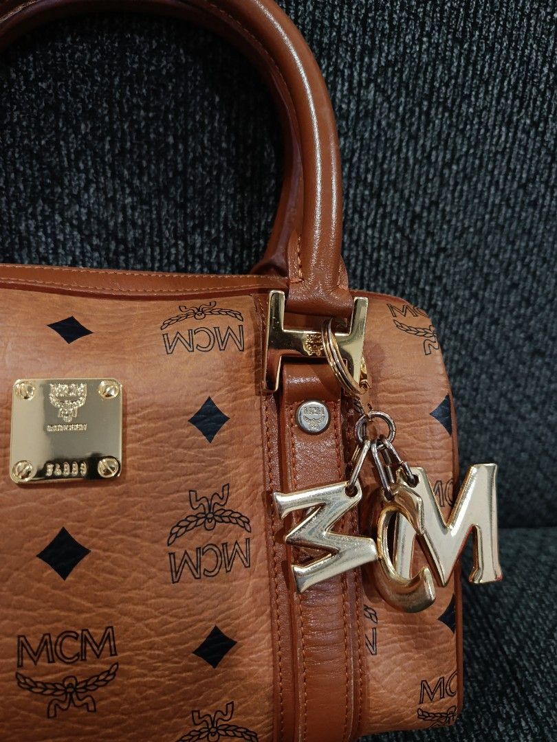 MCM Monogram Boston Bag with Charm (Category: Luxury Bags & Wallets) located in Cabagan. Submitted by blessingma81004 (Listing ID 1457729890, Image 2). Description: - Classic MCM monogram Boston bag - Color: Brown and black - Signature MCM charm included - Gold hardware details - Top handles for comfortable carrying - Secure zipper closure - Ideal for everyday use.