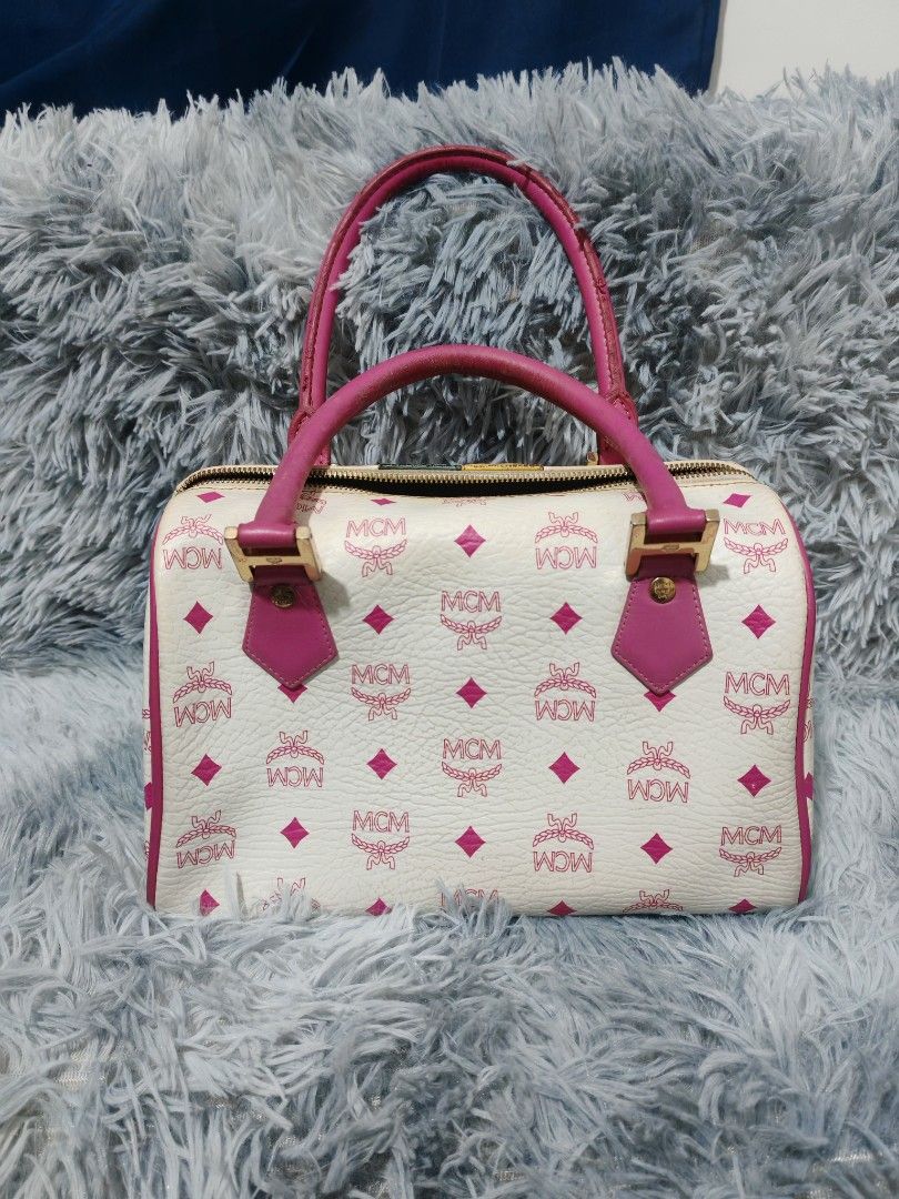 MCM White Monogrammed Boston Bag with Pink Trim (Category: Luxury Bags & Wallets) located in Manila. Submitted by camellesal67218 (Listing ID 1457769812, Image 2). Description: - White MCM Boston bag with signature monogram print. - Pink leather trim and handles. - Central lion emblem with colorful patches. - Zipper closure. - Interior: 1 zippered pocket, 1 slip pocket. - Exterior shows some signs of wear. - Interior is clean..