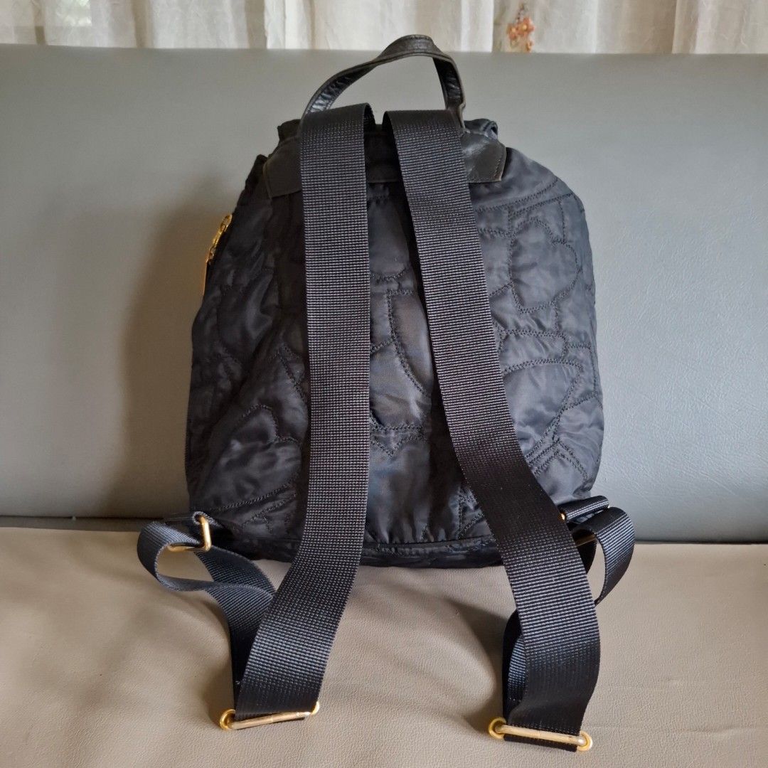 Moschino Cheap and Chic Quilted Heart Black Backpack (Category: Backpacks) located in Don Carlos. Submitted by PphiXi_Finds (Listing ID 1457805638, Image 3). Description: Black quilted backpack with heart pattern. Gold hardware details. Front zip pocket and main drawstring closure. Adjustable shoulder straps. Includes a cute heart charm with 'Cheap and Chic by Moschino' engraving. Great for everyday use..
