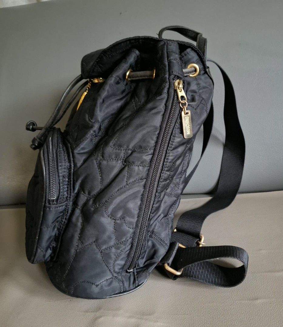 Moschino Cheap and Chic Quilted Heart Black Backpack (Category: Backpacks) located in Don Carlos. Submitted by PphiXi_Finds (Listing ID 1457805638, Image 2). Description: Black quilted backpack with heart pattern. Gold hardware details. Front zip pocket and main drawstring closure. Adjustable shoulder straps. Includes a cute heart charm with 'Cheap and Chic by Moschino' engraving. Great for everyday use..