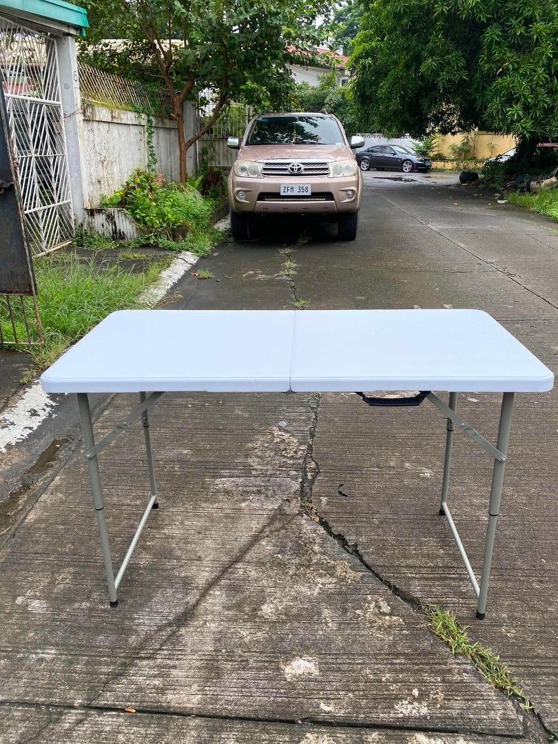 4ft adjustable White Folding Table with Metal Legs (Category: Tables & Sets) located in Manila. Submitted by shairatorres (Listing ID 1457974395, Image 2). Description: - Portable and foldable table, perfect for events or extra space. - Sturdy white tabletop with durable grey metal legs. - Folds flat for convenient storage and transport. - Features a built-in handle for easy carrying. - Versatile for both indoor and outdoor use. - Approximately 4