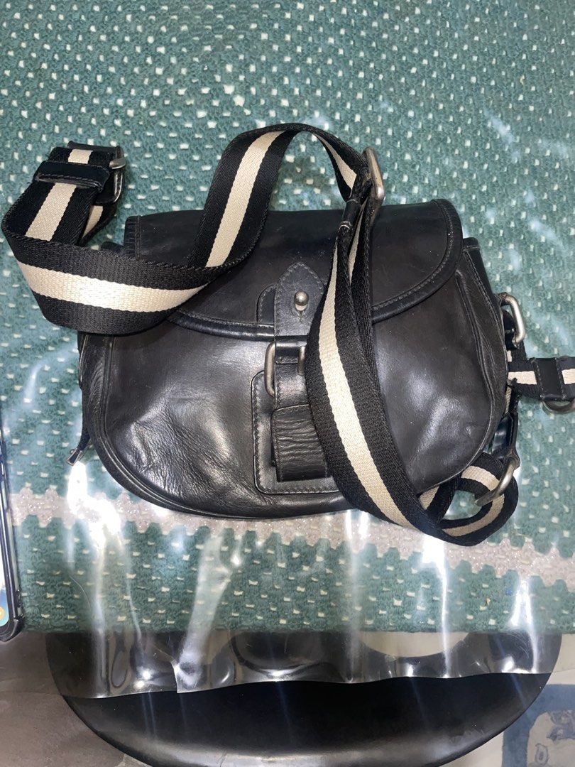 Bally Black Leather Crossbody Bag with Striped Strap (Category: Cross-body Bags) located in Cavite. Submitted by msandysgoodies (Listing ID 1458020145, Image 1). Description: - Authentic Bally black leather crossbody bag - Features the iconic Bally striped strap - Secure buckle closure on the front flap - Interior includes a zippered pocket and a main compartment - Perfect size for carrying daily essentials - Shows some signs of wear on the leath